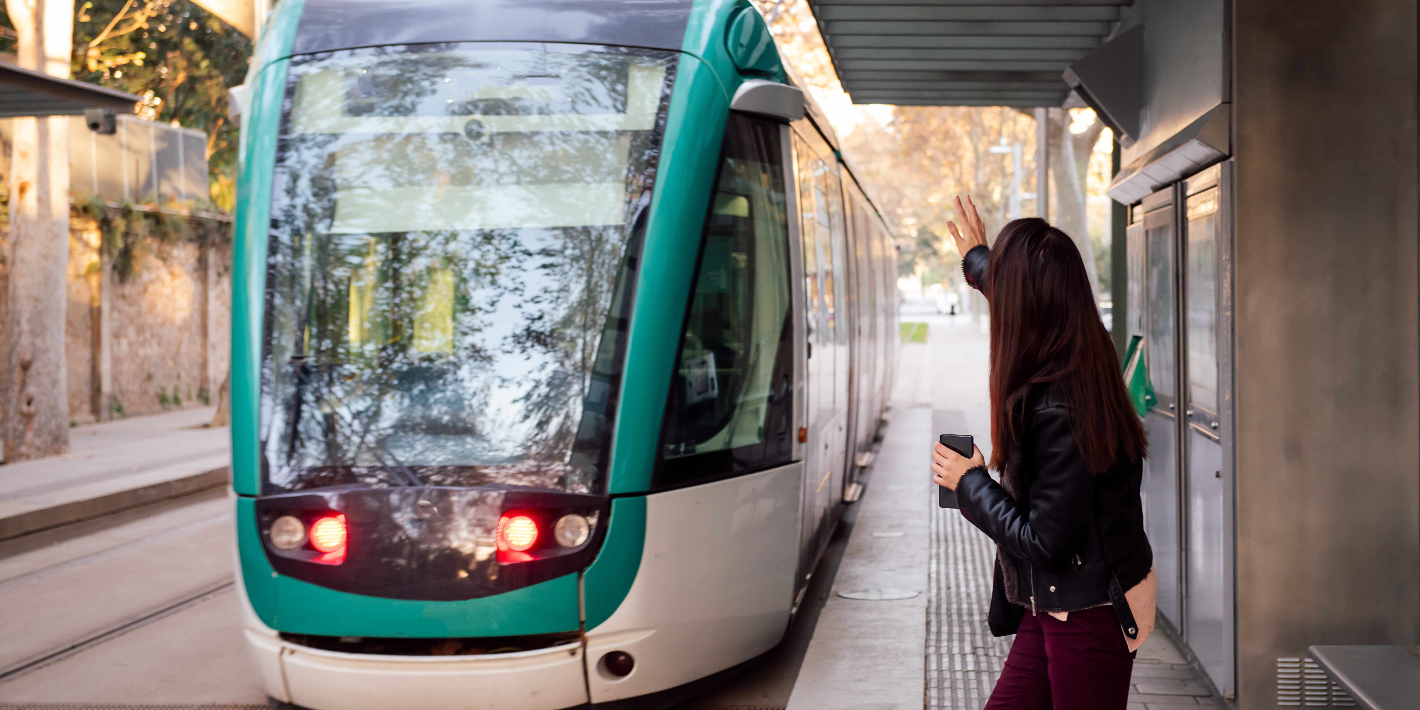 woman raising her hand to call for the streetcar mobilité durable, mobilité, train, tramway, transport